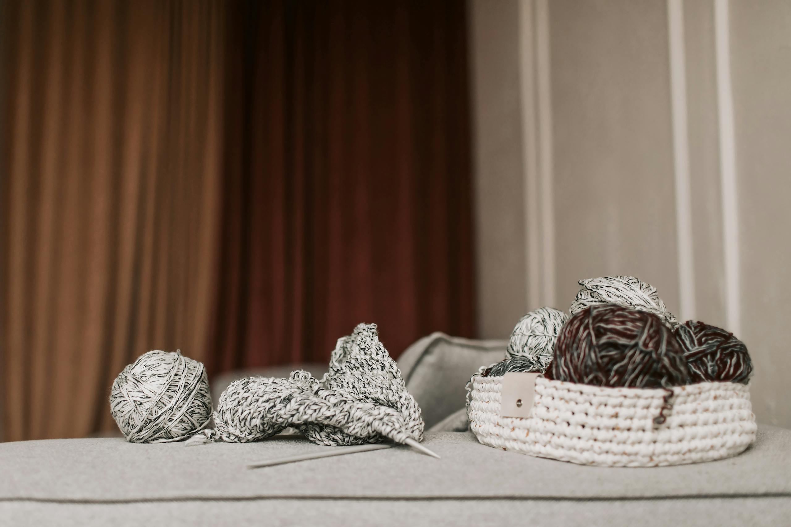 A cozy indoor setting with knitting materials, including yarn balls and a woven basket.