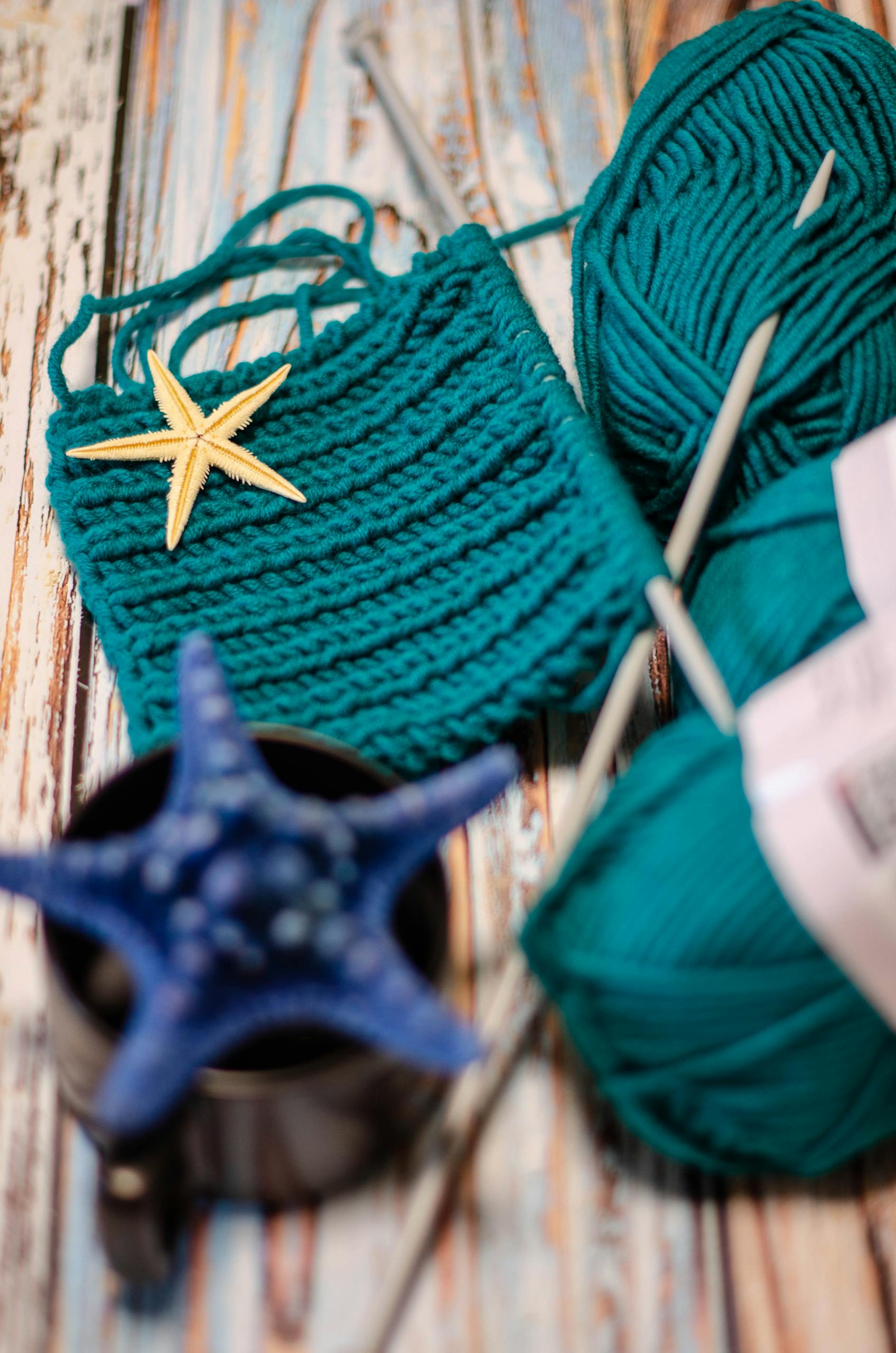 Coastal knitting scene featuring teal yarn, knitting needles, and starfish accents.