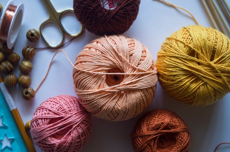 Colorful yarn balls with crafting tools perfect for knitting or DIY projects.